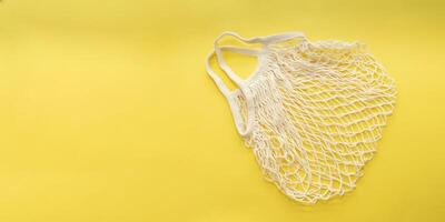 Reusable cotton shopping string bag on bright yellow background. Copy space. zero waste concept, no plastic. photo