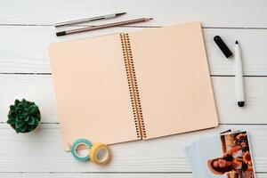 Creative workspace with open notebook, stationery, and decorative items on a wooden table photo