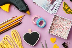 Crafting supplies arranged on a pink background, including glue gun, scissors, and decorative items for DIY projects photo