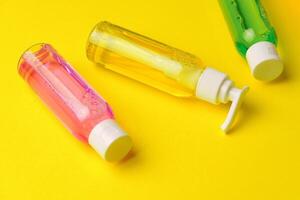 Colorful Bottles of Liquid Soap on Yellow Background photo