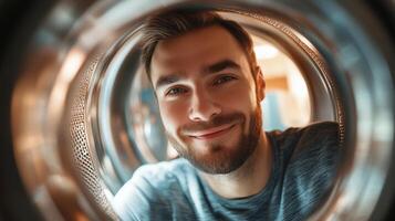 A man smiling from inside a laundry machine in a cozy laundry room during the afternoon with a playful attitude photo