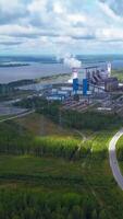 Top view of power plant on lake shore. Clip. Factory pipes on background of lake and green forest. Landscape with power station and pipes by lake in summer video