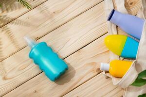 Sunscreen cream bottles in beach bag on wooden background photo