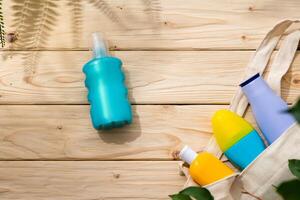 Sunscreen cream bottles in beach bag on wooden background photo