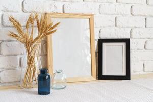 Mockup with a frame and dry flowers in a vase on a white table photo