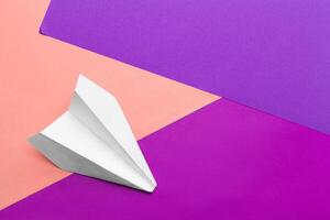 white paper airplane on a color block paper background photo