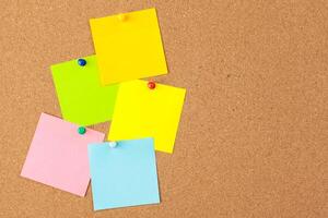 Cork board with several colorful blank notes with pins photo