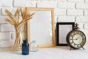 Mockup with a frame and dry flowers in a vase on a white table photo