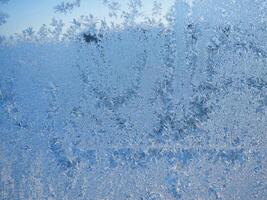 Winter frost patterns on glass. Ice crystals or cold winter background.Beautiful natural frosty pattern on winter window photo