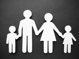 Symbol of a man made of white paper on a black background. The concept of the family. Mom, dad, daughter and son. photo