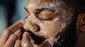 A man applies a cleansing scrub to his face to rejuvenate his skin during a morning skincare routine at home photo
