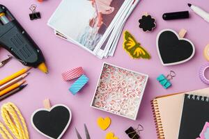 Crafting supplies arranged on a pink background, including glue gun, scissors, and decorative items for DIY projects photo