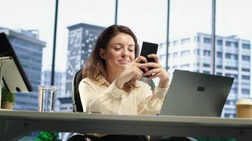 Business director texting messages and discussing about enterprise performance, sharing insight on updates and details. Young entrepreneur using her personal phone on social media. Camera A. video