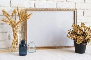 Mockup with a frame and dry flowers in a vase on a white table photo
