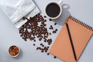 Cup of coffee with notebook on gray background top view photo