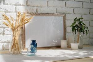 Mockup with a frame and dry flowers in a vase on a white table photo