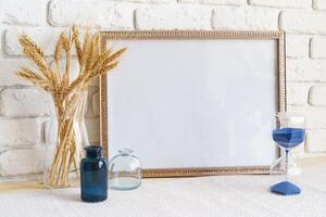 Mockup with a frame and dry flowers in a vase on a white table photo