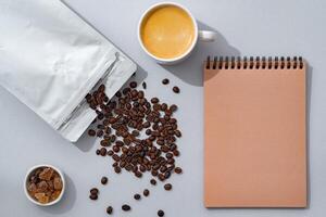 Cup of coffee with notebook on gray background top view photo