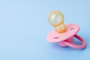 Orthodontic pacifier on a blue background. Pink baby pacifier photo