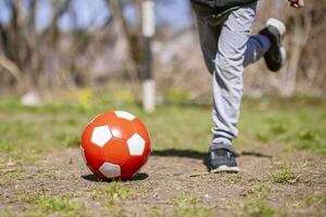 Boy is playing with soccer ball on footballs field in the park. Kids activities photo