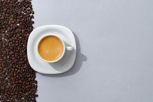 Cup of coffee with coffee beans on paper background. Top view photo
