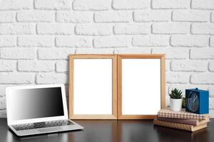 Worktable with laptop, stationery and decorations in home office with blank photo frame