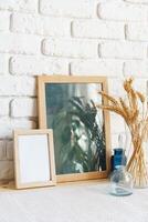Mockup with a frame and dry flowers in a vase on a white table photo