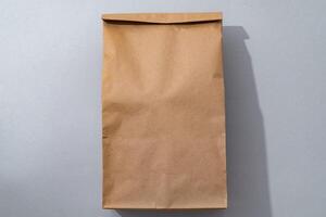 Craft paper bag on gray background flat lay top view photo