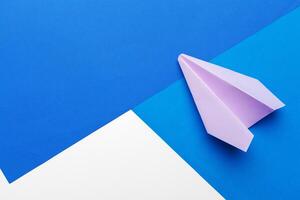 Flat lay of white paper plane and blank paper on pastel blue color background photo