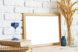 Vase with ears of wheat and photo frames against brick wall