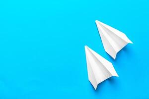 Flat lay of white paper plane and blank paper on pastel blue color background photo