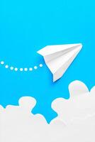 Flying paper plane in the clouds on a blue background. Concept of flight, travel, transfer photo