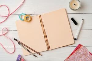 Creative workspace with open notebook, stationery, and decorative items on a wooden table photo