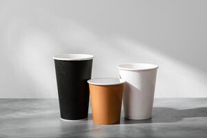 Stack of coffee cups in various colors with lids on a gray surface photo