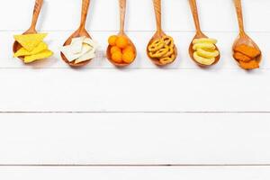 Mix of snacks . pretzels , crackers , chips and nachos on the table photo
