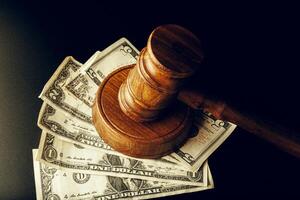 Wooden judge gavel on US dollar banknotes closeup. Justice corruption concept photo