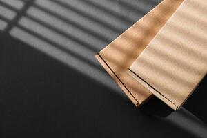 Various sizes of brown cardboard boxes arranged on a black surface with soft lighting effects during the day photo