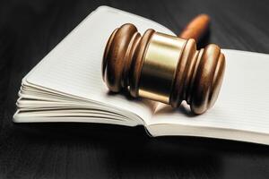 Brown wooden judge mallet on the background of open book photo