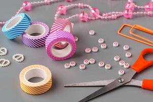 Crafting supplies arranged for a DIY project on a gray table with scissors, washi tape, and decorative items photo