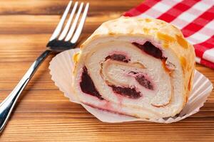 Meringue roll cake with cream on wooden table photo