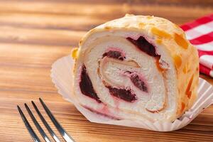 Meringue roll cake with cream on wooden table photo