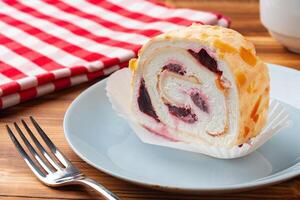 Meringue roll cake with cream on wooden table photo