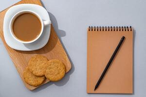 Cup of coffee with notebook on gray background top view photo
