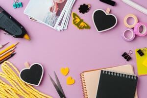 Crafting supplies arranged on a pink background, including glue gun, scissors, and decorative items for DIY projects photo