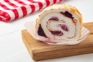 Meringue roll cake with cream on wooden table photo