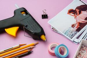 Crafting supplies arranged on a pink background, including glue gun, scissors, and decorative items for DIY projects photo