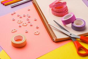 Scissors and decorative tape on colorful craft paper in a bright workspace photo