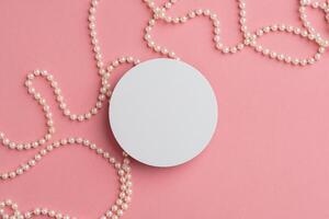 Elegant Round White Surface Surrounded by String of Pearls on Soft Pink Background photo