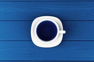Top view of a cup of coffee on saucer on classic blue background photo