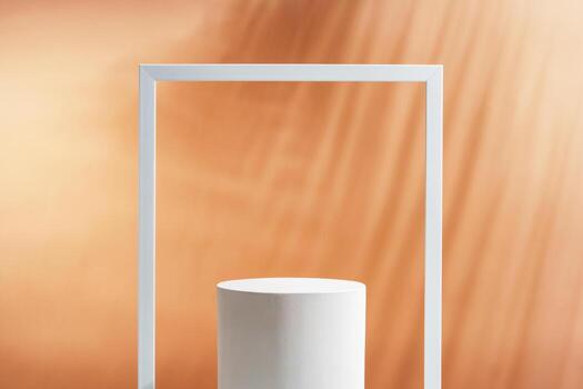 Minimalistic display of a white cylindrical object framed by a white rectangular border against a soft orange background photo